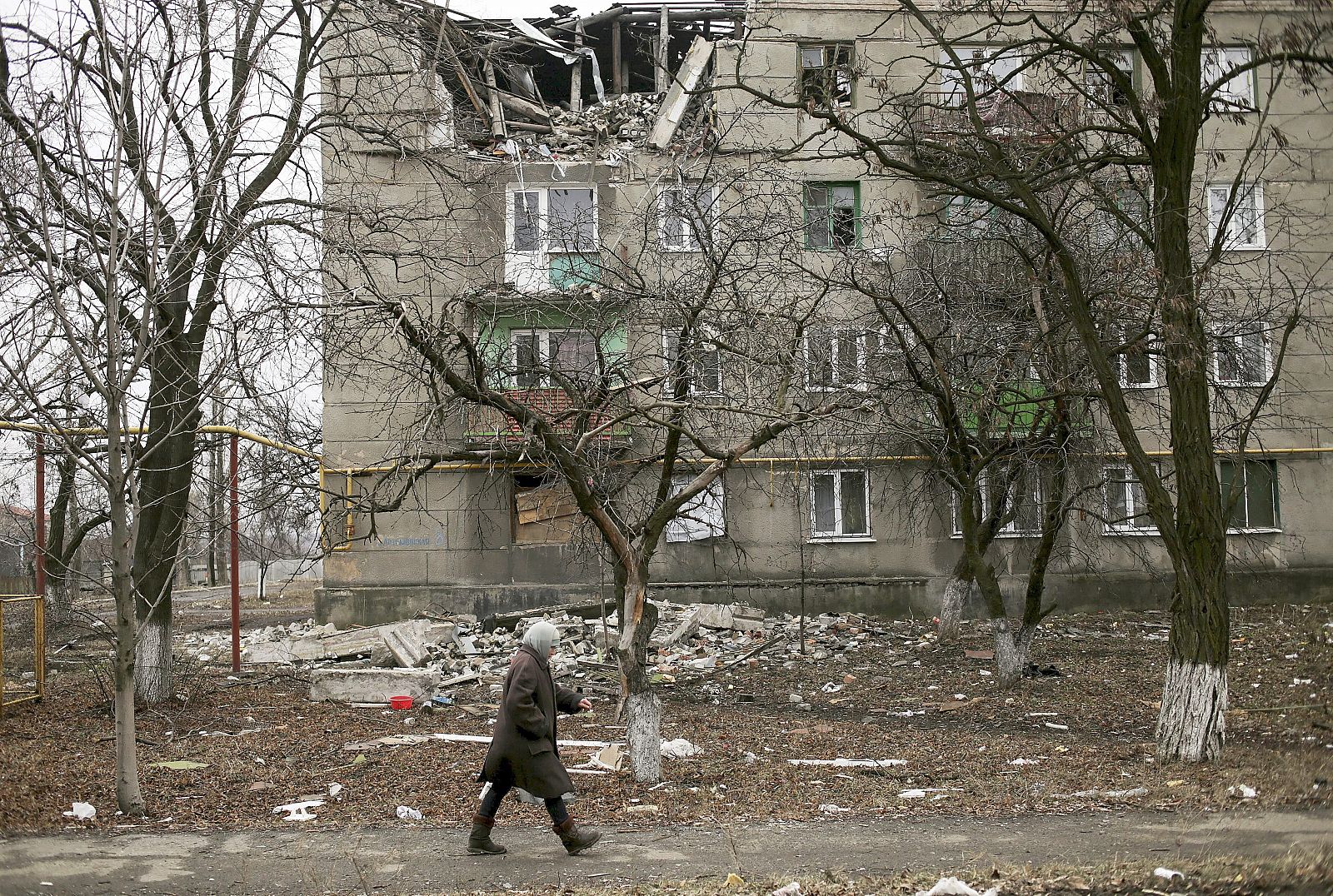 Una mujer camina por la dañada ciudad de Popasne, en el este de Ucrania