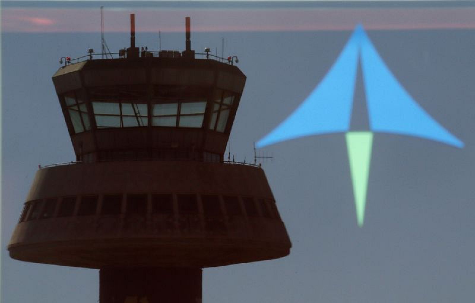 Reflejo de una torre de control sobre un cristal con el logo de AENA