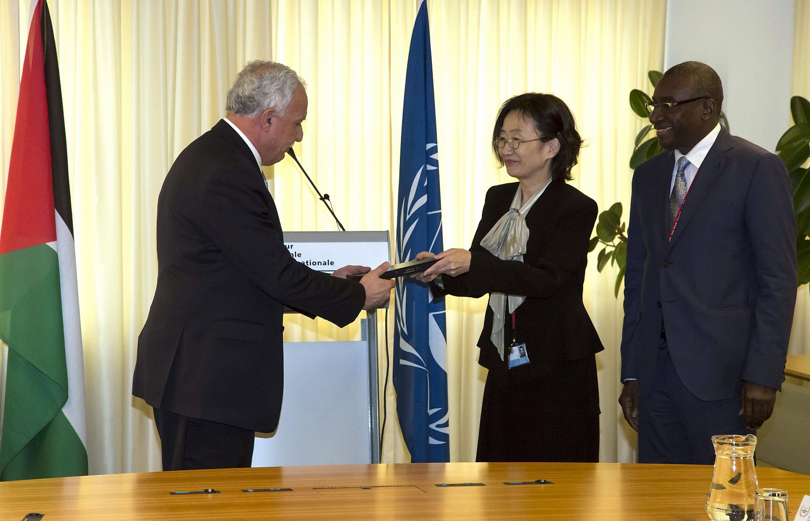 Fotografía cedida por la Corte Penal Internacional donde se ve a su vicepresidenta Kuniko Ozaki (centro) entregando una copia del Estatuto de Roma al ministro de Exteriores de Palestina, Riad Al-Malki.