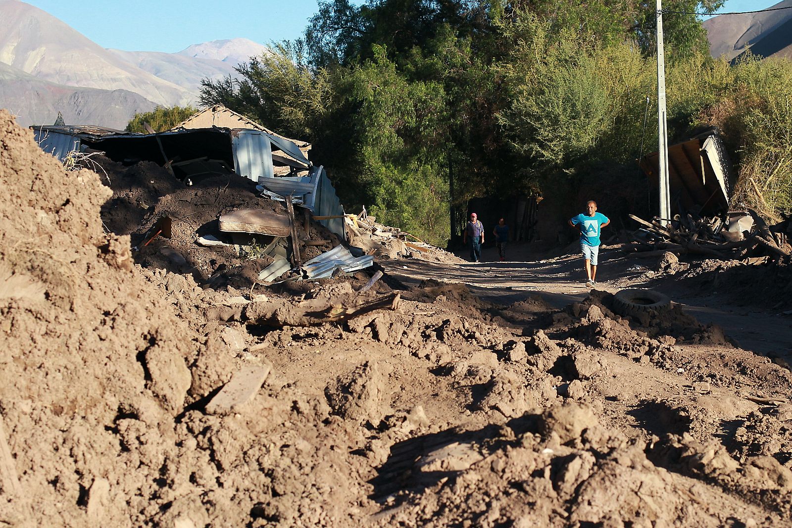 Varias personas transitan junto a escombros dejados tras fuertes lluvias en Chile