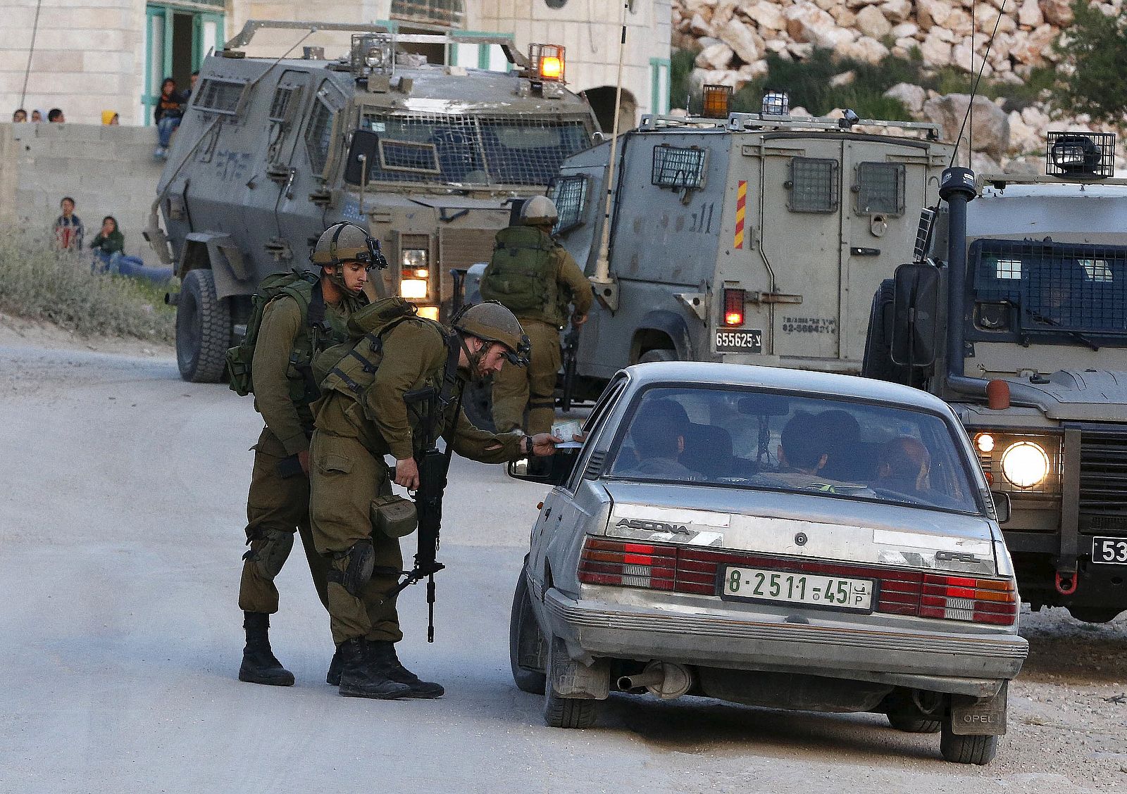 Israeli soldiers stop a car as they search for a missing Israeli near the West Bank city of Hebron