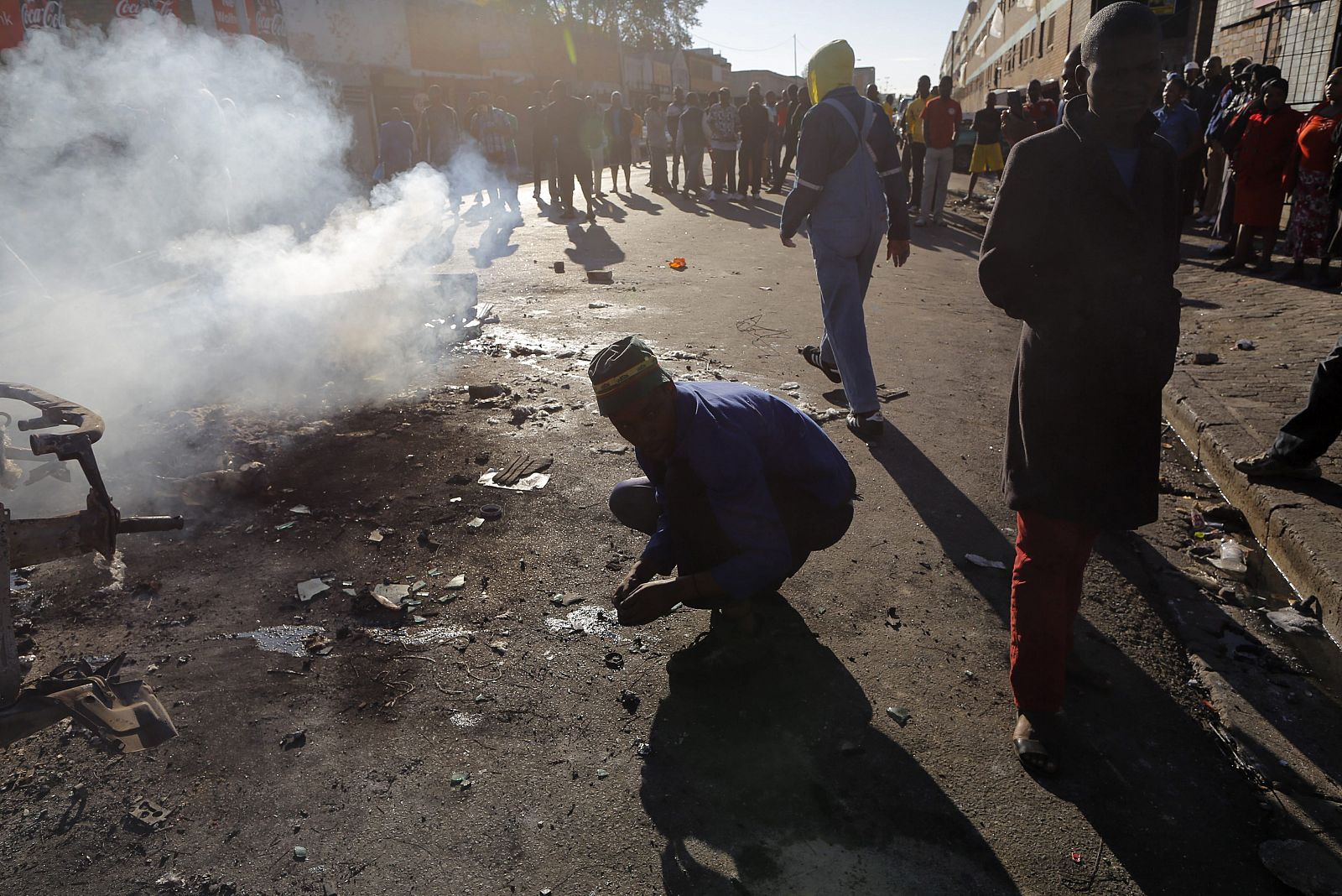 Vecinos partidarios de la expulsión de extranjeros observan un coche incendiado en un nuevo ataque xenófobo registrado en el centro de Johannesburgo (Sudáfrica), el pasado viernes 17 de abril.