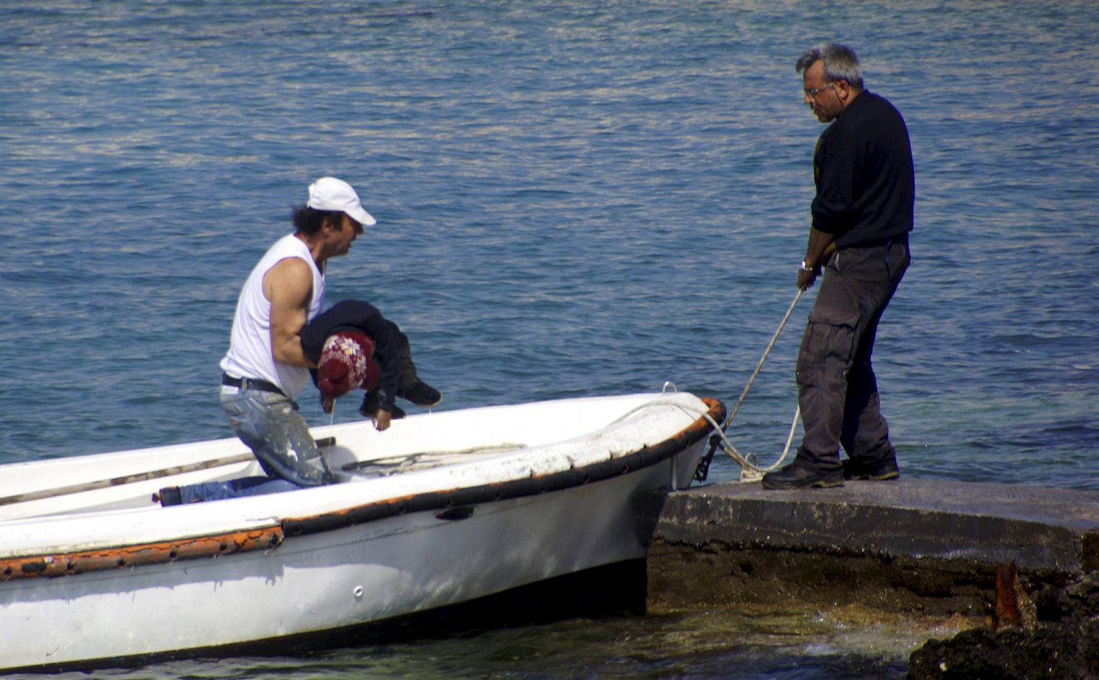 Un hombre recupera el cadáver de un niño migrante en la costa de la isla griega de Rodas.