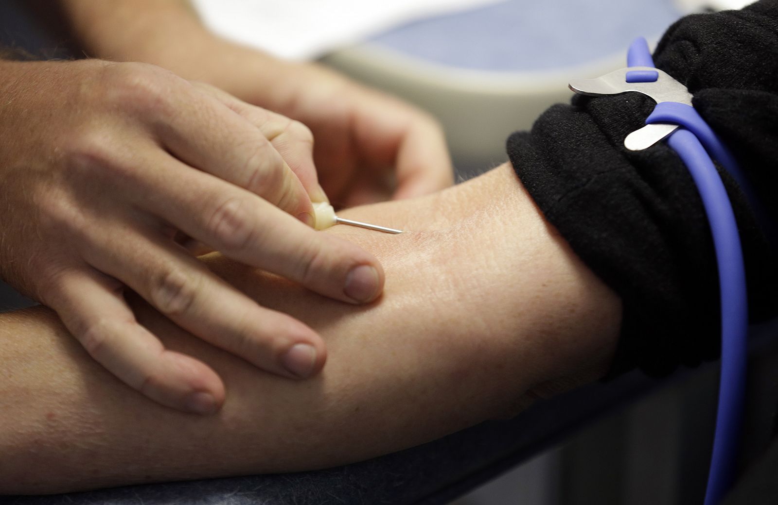Un médico inserta una aguja en el brazo durante una donación de sangre