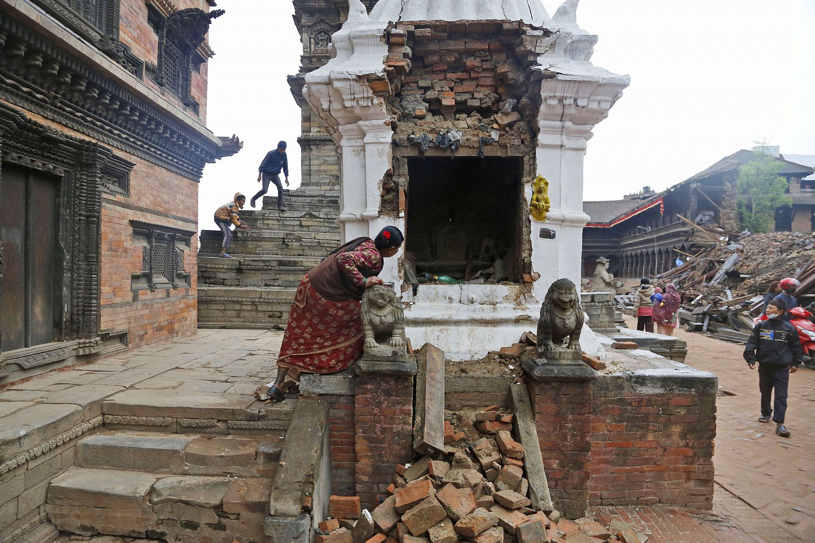 Una mujer inspecciona el interior de las ruinas de un templo destruido por el terremoto