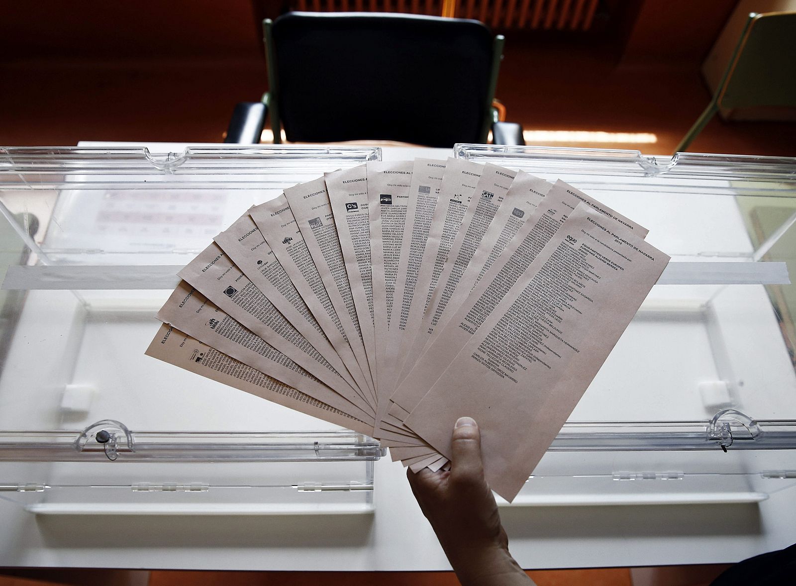 Una persona muestra papeletas del 24M junto a una de las urnas