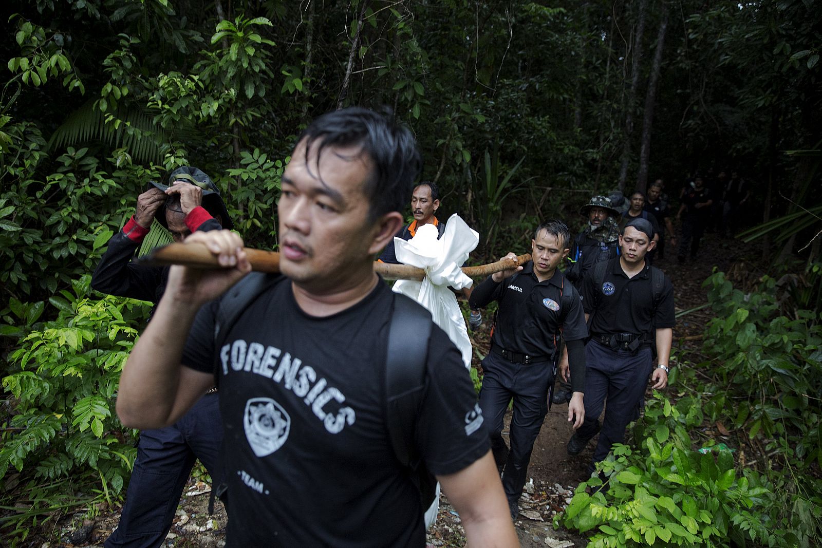 Miembros de la Policía forense transportan restos humanos hallados en una de los campamentos de los traficantes de personas, en Malasia