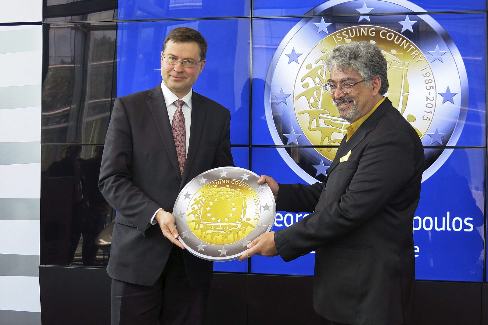 El vicepresidente de la CE para el Euro, Valdis Dombrovskis, junto al ganador del concurso impulsado por la Comisión para elegir una moneda conmemorativa, George Stamatopoulos (Banco de Grecia)