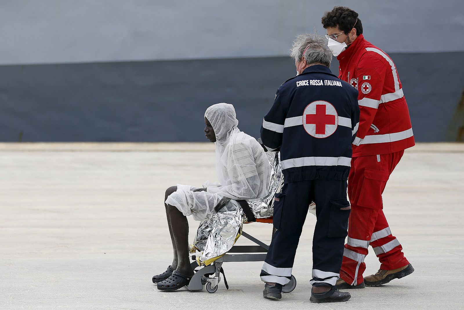 Miembros de Cruz Roja atienden a un migrante rescatado en el Mediterráneo en el puerto de Augusta, Sicilia.