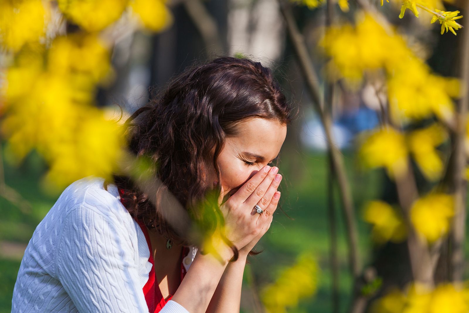 Una mujer estornudando en el campo.