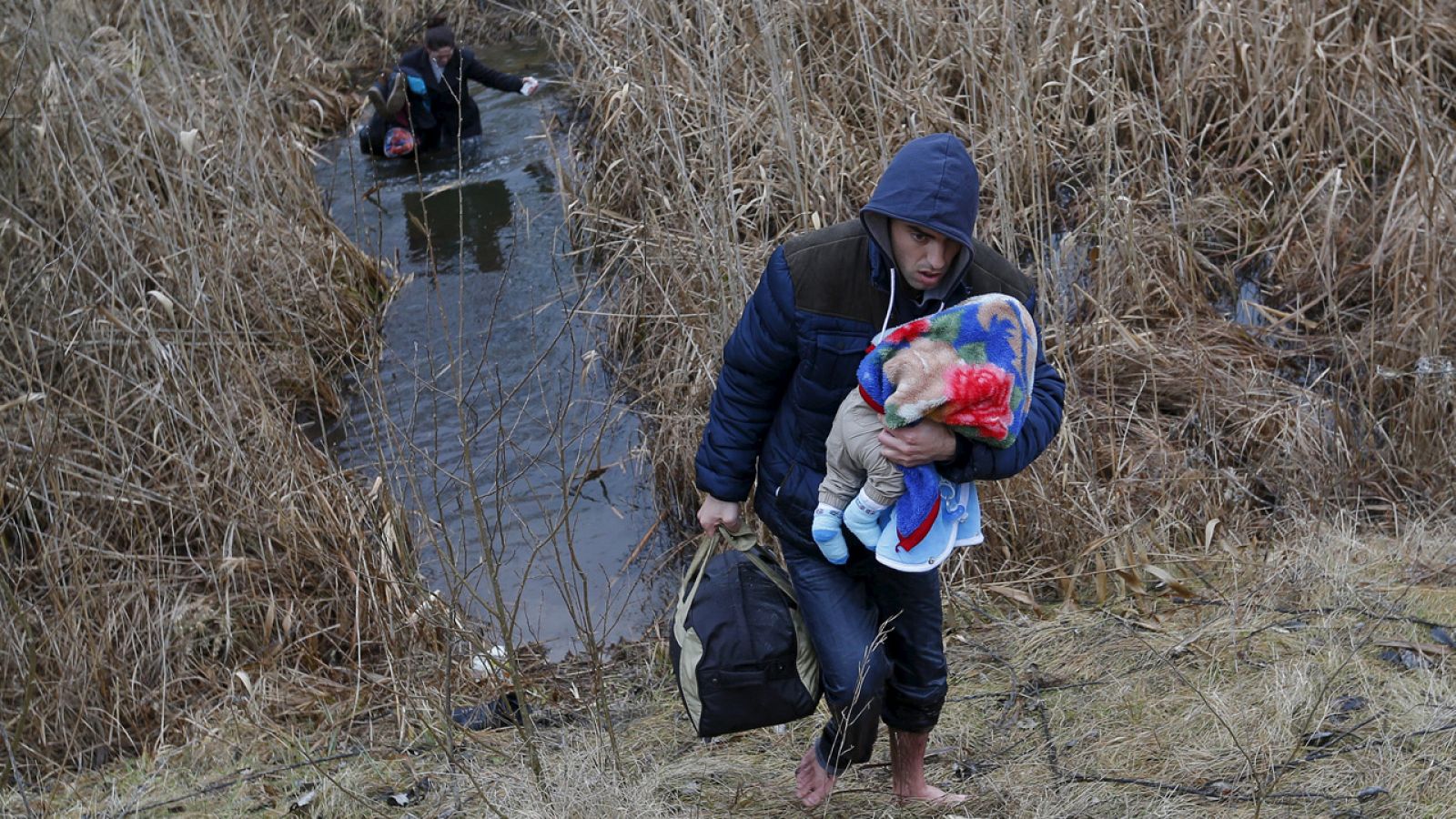 Una familia kosovar cruza clandestinamente a través de un cauce de agua la frontera entre Serbia y Hungría cerca de la localidad de Asotthalom el 6 de febrero de 2015.