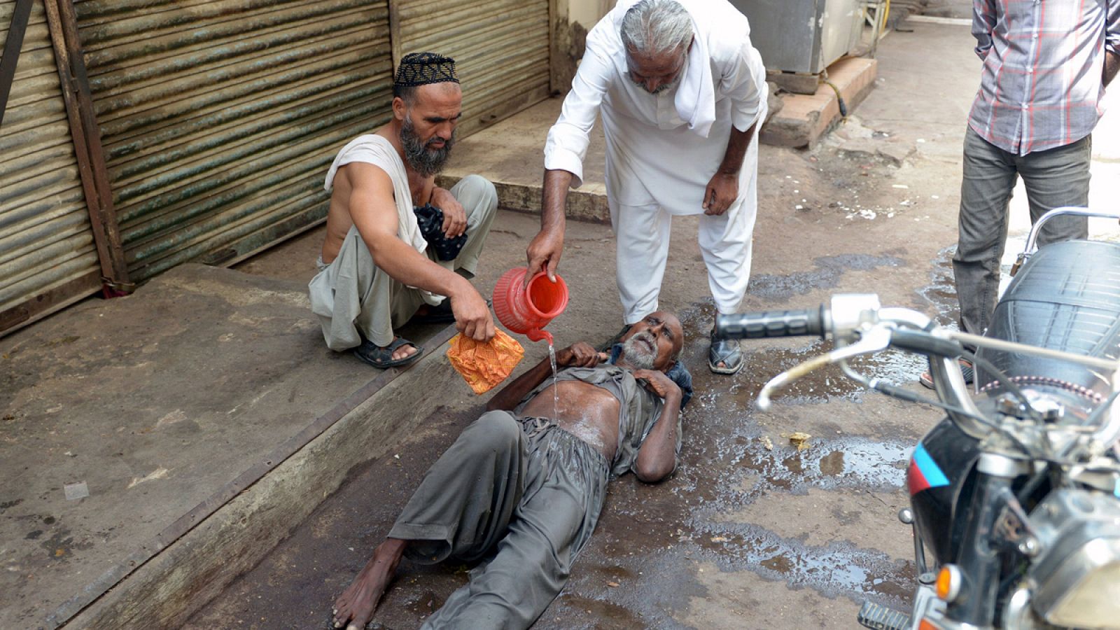 Un hombre afectado por el calor recibe la ayuda de varias personas en Karachi, Pakistán