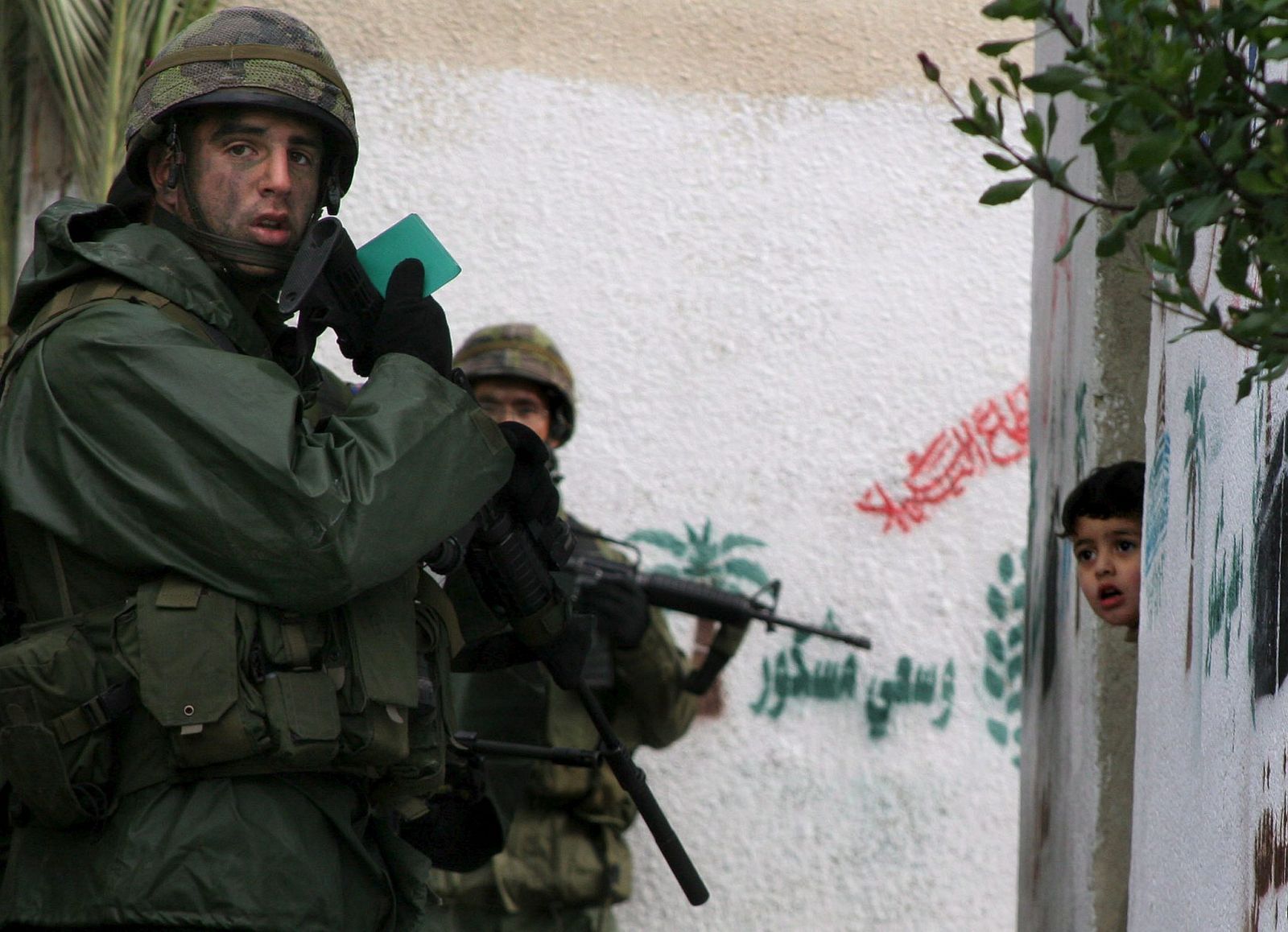 Un niño palestino mira a hurtadillas desde su casa a los soldados israelíes en la ciudad cisjordana de Hebrón 17/01/06