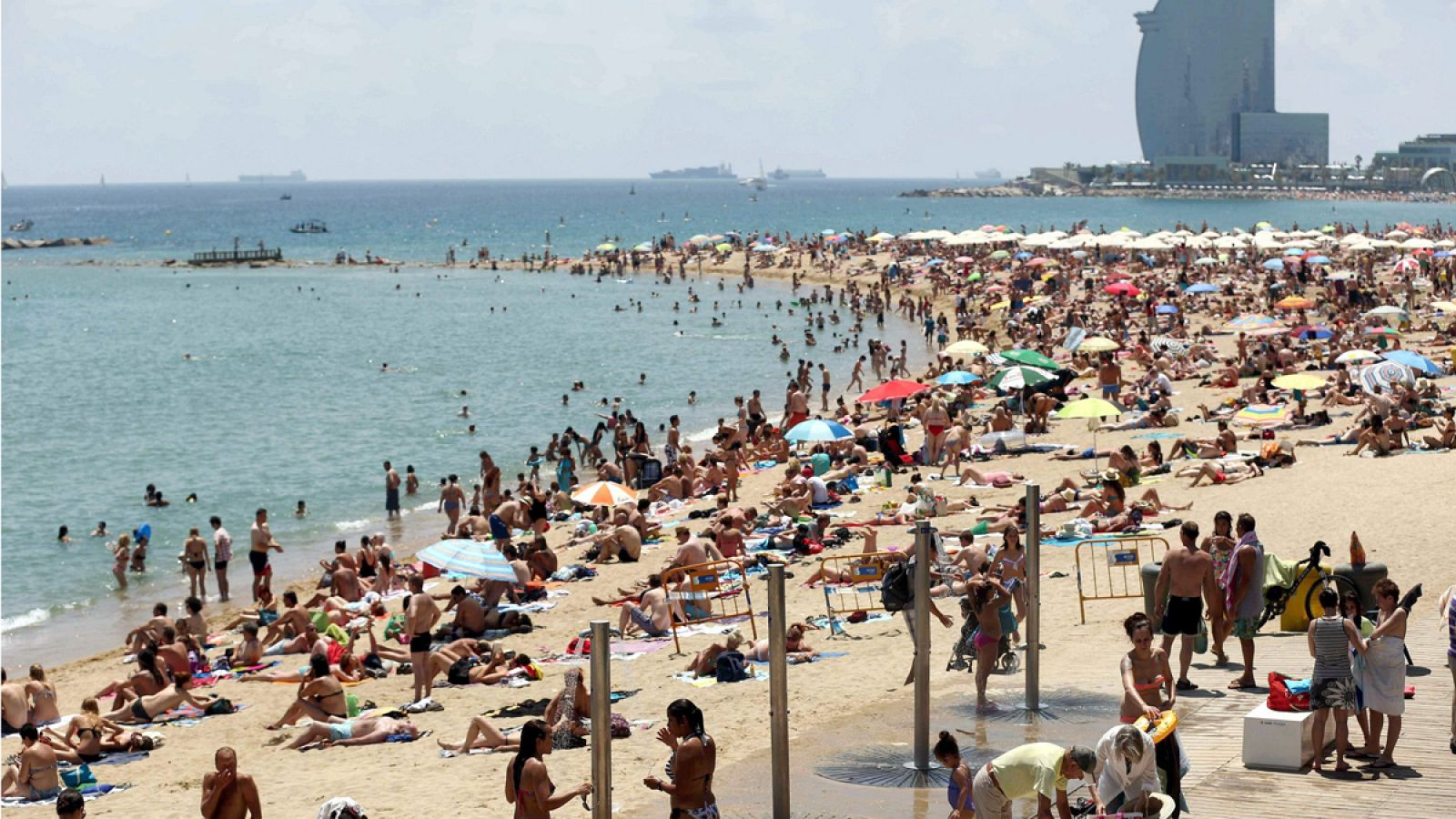 La playa de la Barceloneta llena de gente que disfruta del mar en Barcelona