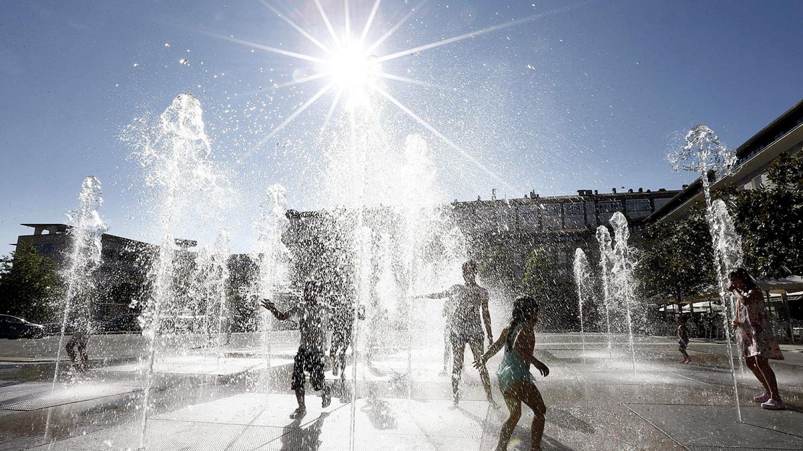 Un grupo de jóvenes disfrutan del baño con unos chorros de agua en Pamplona