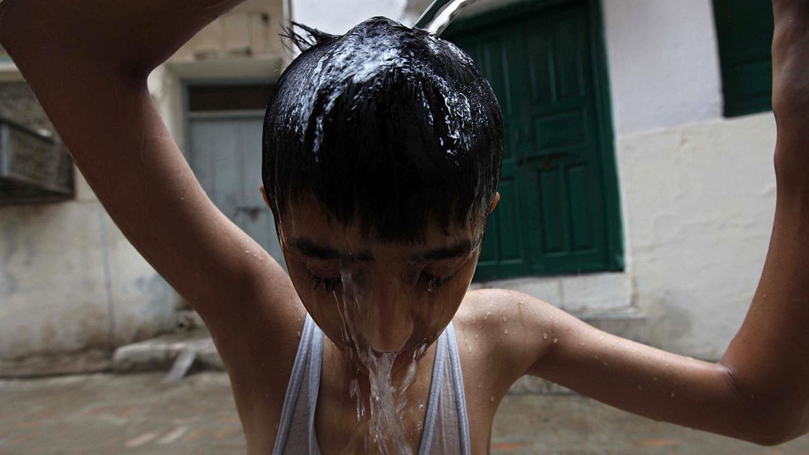 Un joven se refresca con agua en Peshawar durante la ola de calor.