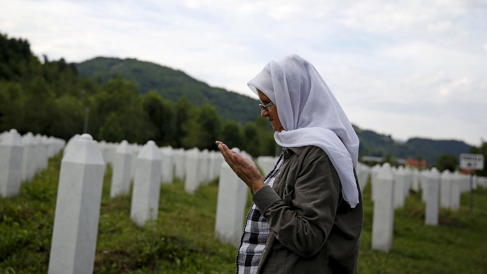 Hajra Catic prays near the grave of her husband at the Memorial center in Potocari