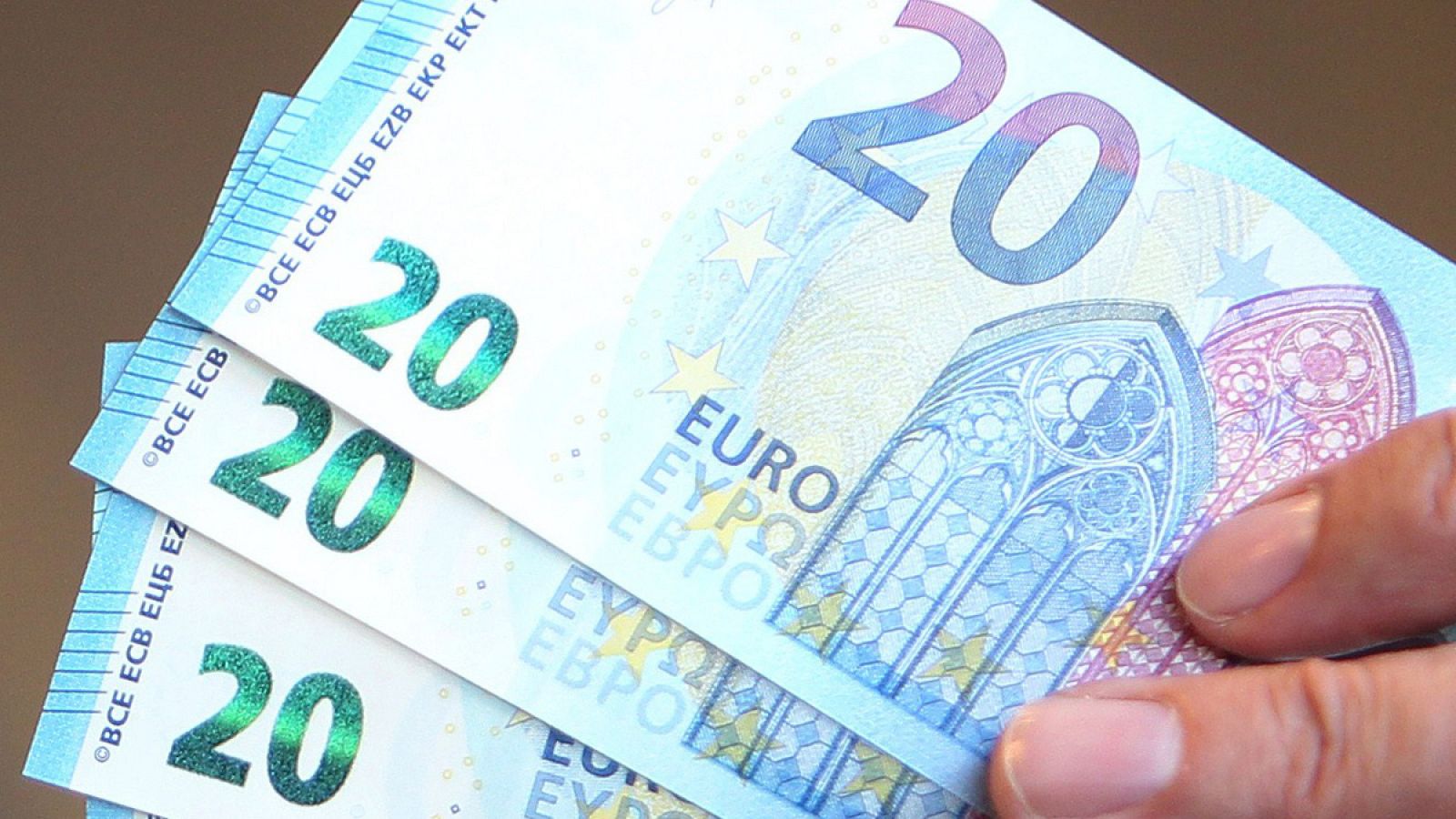 Una mano sostiene un abanico de billetes de 20 euros