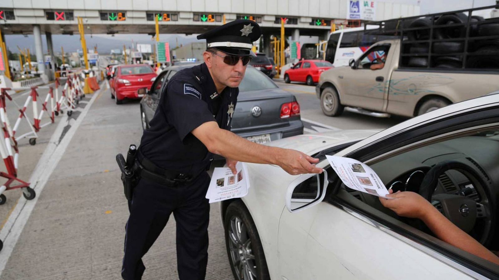Un policía distribuye folletos a los conductores donde se anuncia una recompensa para quien proporcione información que lleve a la recaptura de Joaquin 'El Chapo'