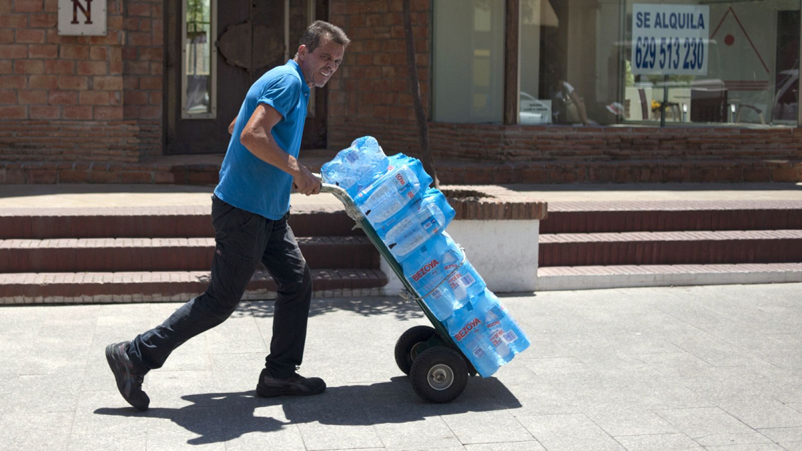 Un hombre empuja una carretilla con botellas de agua en Torremolinos