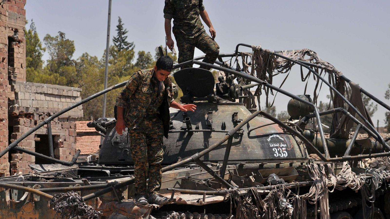 Milicianos kurdos sobre un tanque con anagramas del Estado Islámico en la localidad de Al-Nashwa, el norte de Siria, este domingo.