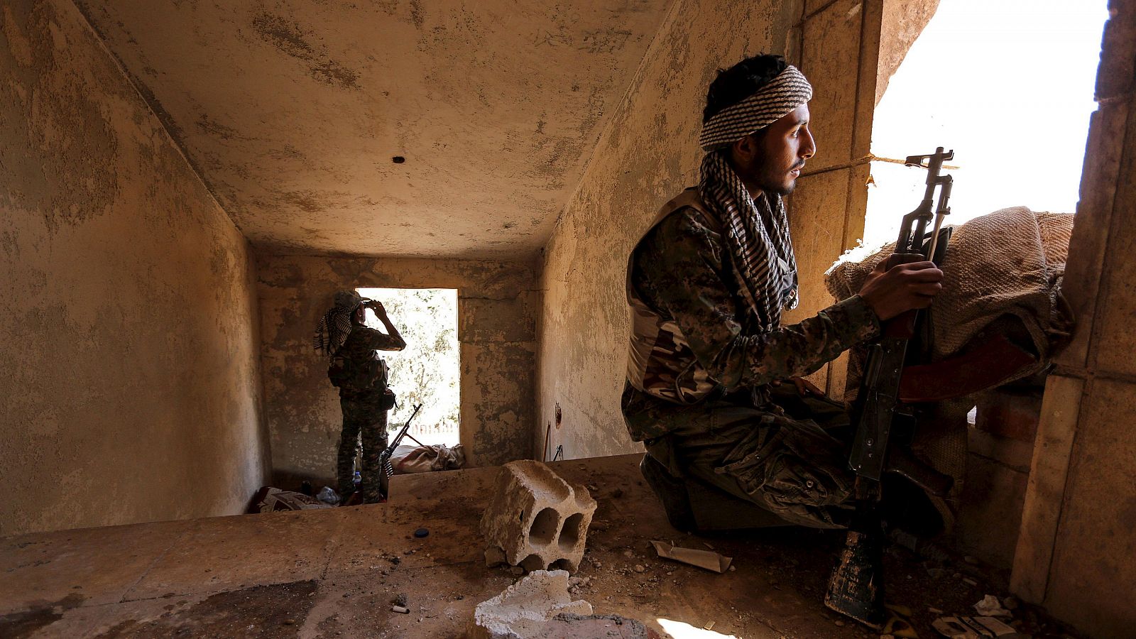 Combatientes kurdos ocupan posiciones dentro de un edificio dañado en Al- Vilat Al- Homor mientras vigilan los movimientos de los combatientes del Estado Islámico