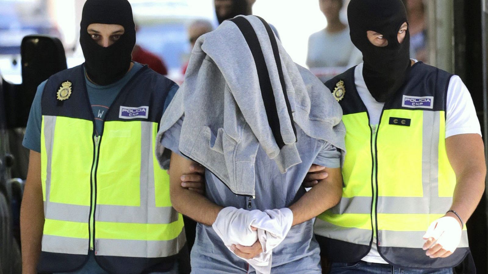 Agentes de la Policía Nacional conducen presunto yihadista con la cabeza tapada el día de la detención