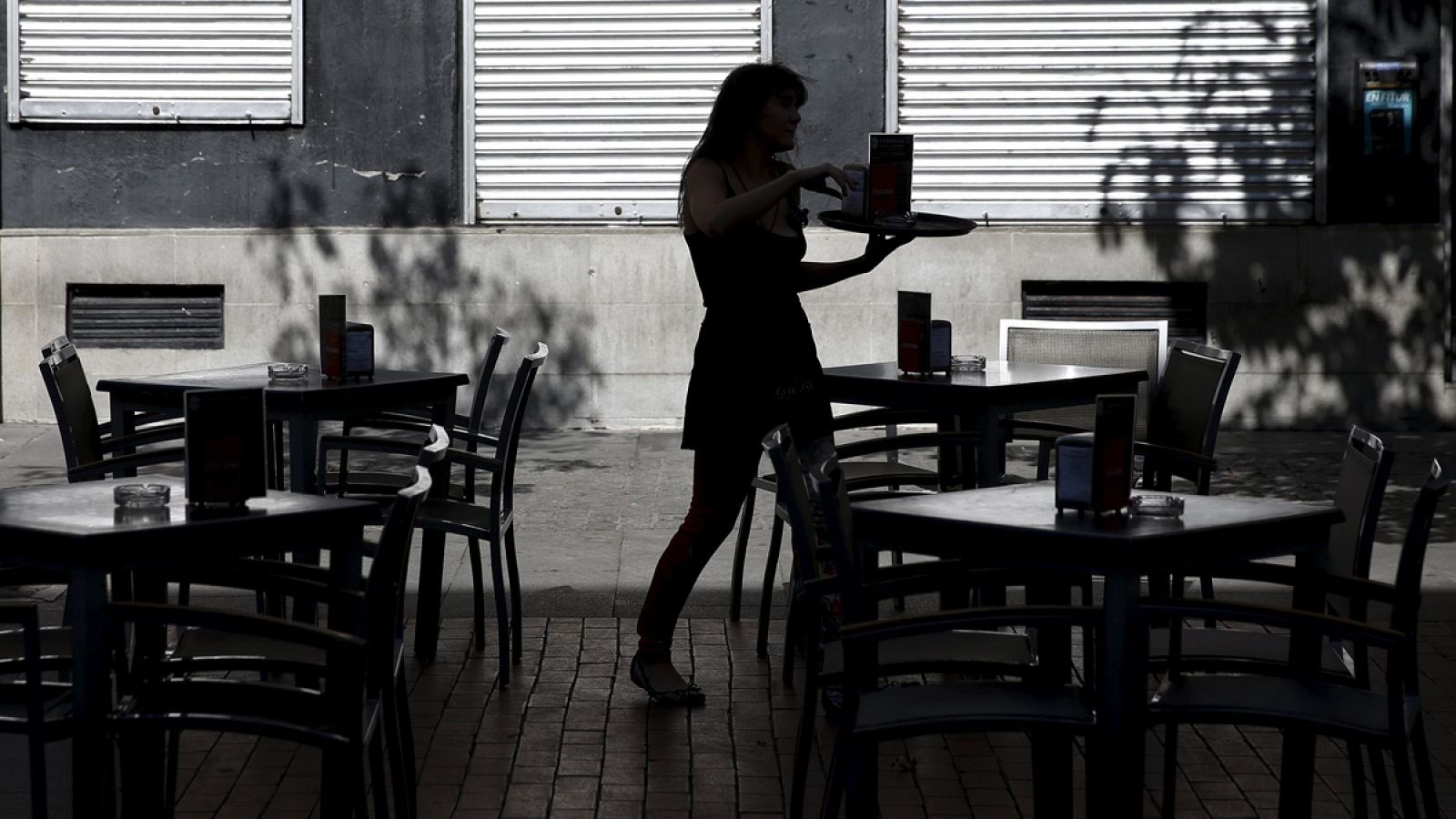 Una camarera prepara las mesas de una terraza en Madrid