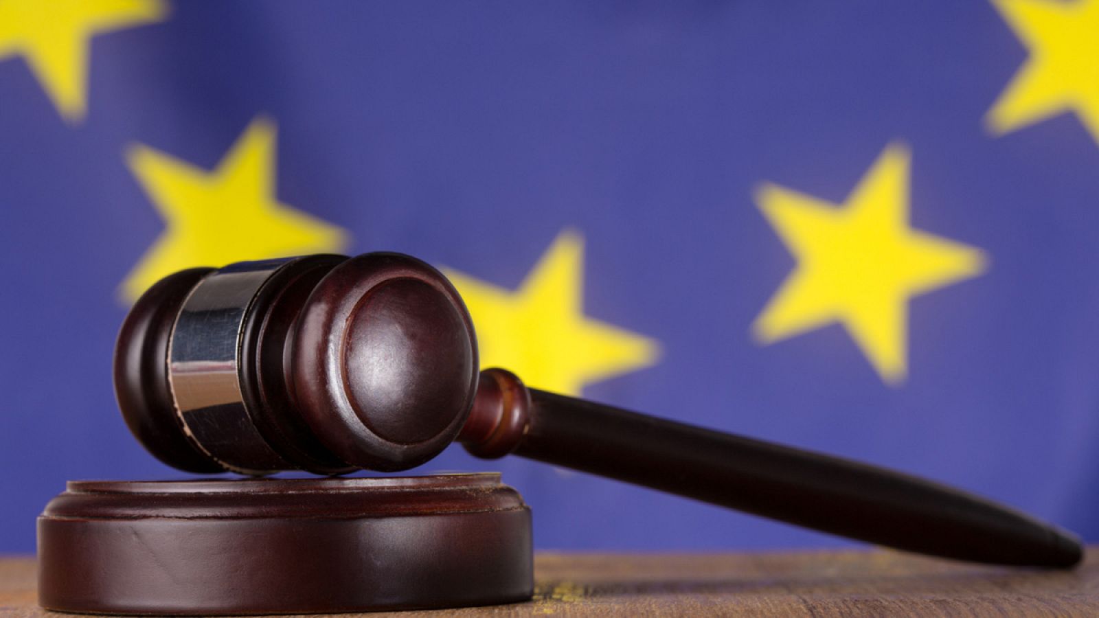 El mazo de un juez con la bandera de la UE al fondo