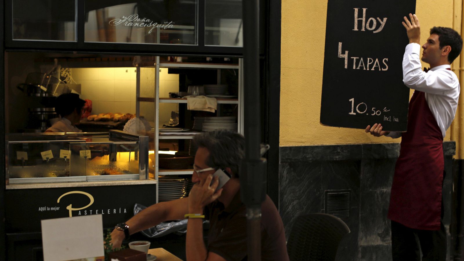 Un camarero instala un cartel con una oferta en Sevilla