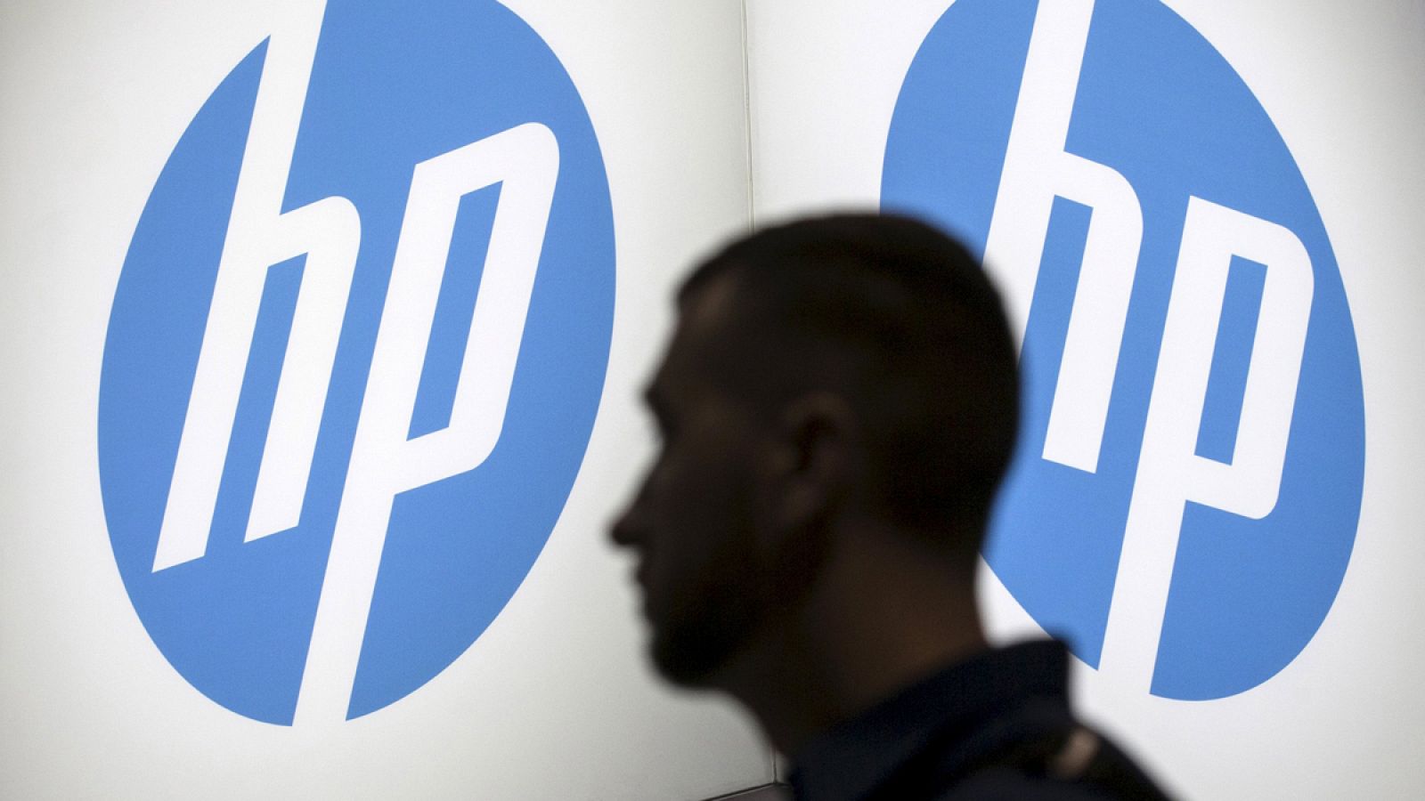 Un hombre pasa por delante de un logo de HP
