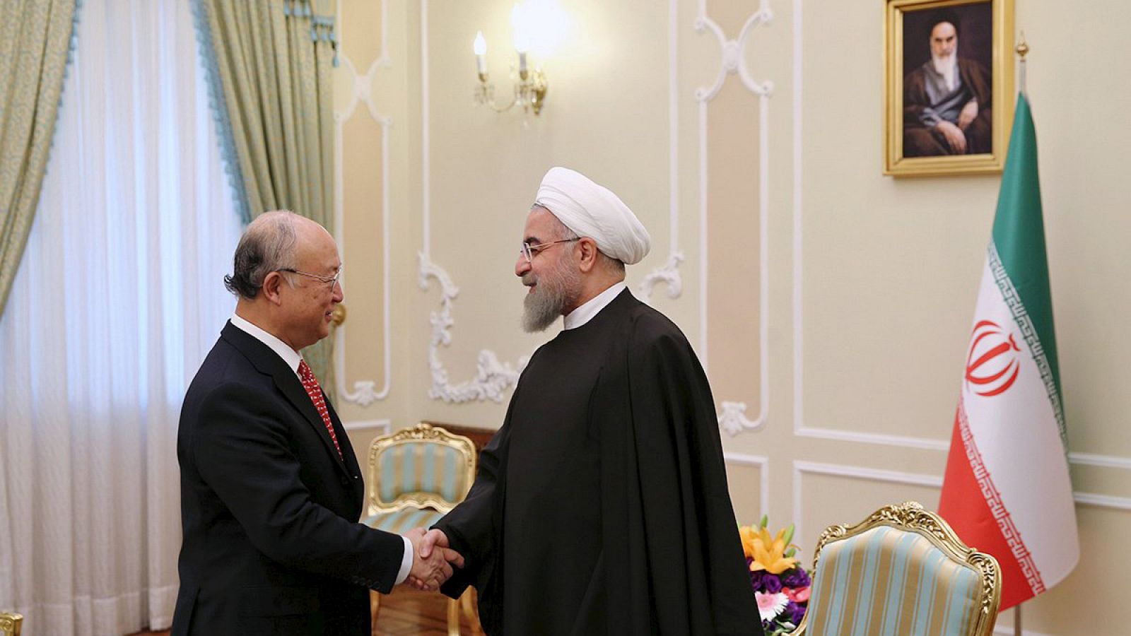 El director de la OIEA Yukiya Amano saluda al presidente iraní Rohani en Teherán