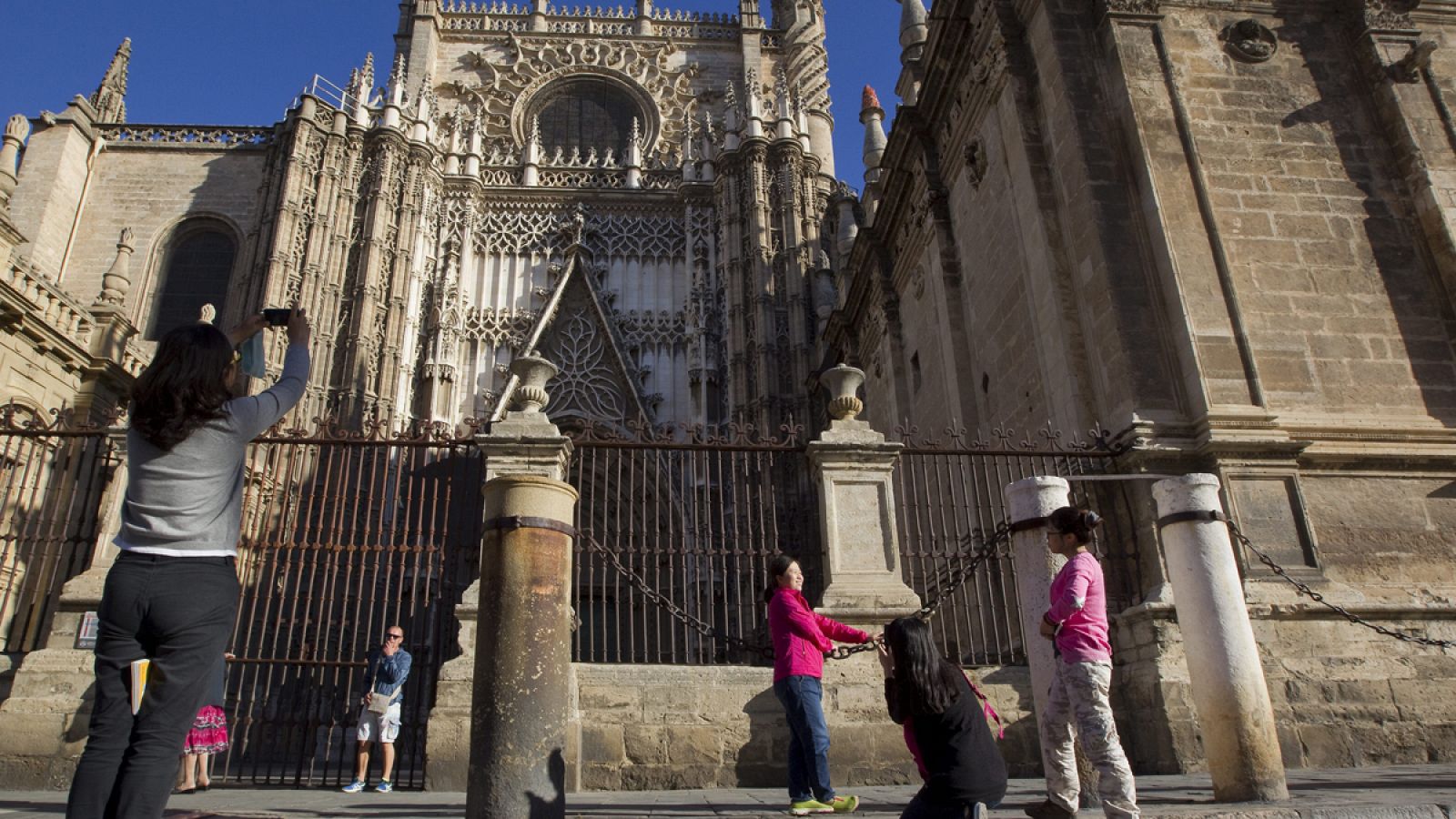 Unas turistas se fotografían delante de la catedral de Sevilla