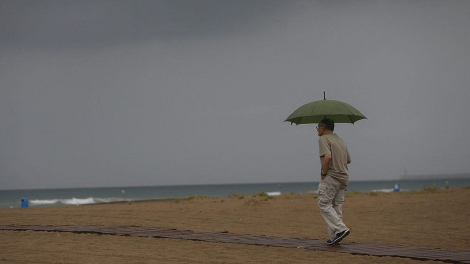 Imagen de archivo de un hombre paseando por la playa con amenaza de tormenta.