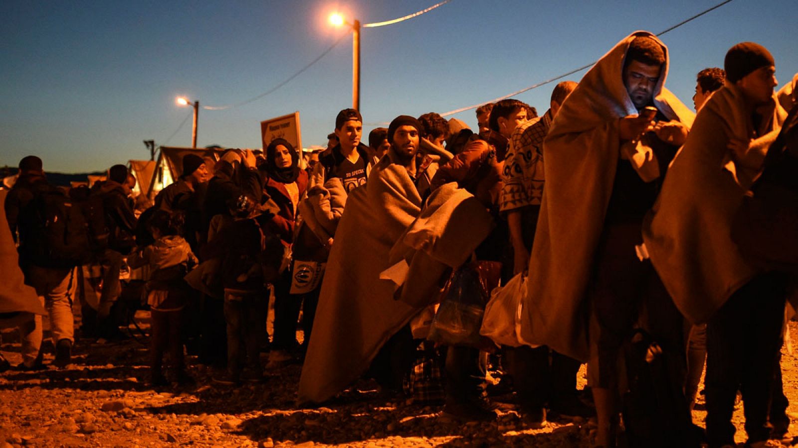 Un grupo de personas esperan para salir del campo de registro y abordar un tren rumbo a la frontera serbia en Macedonia.