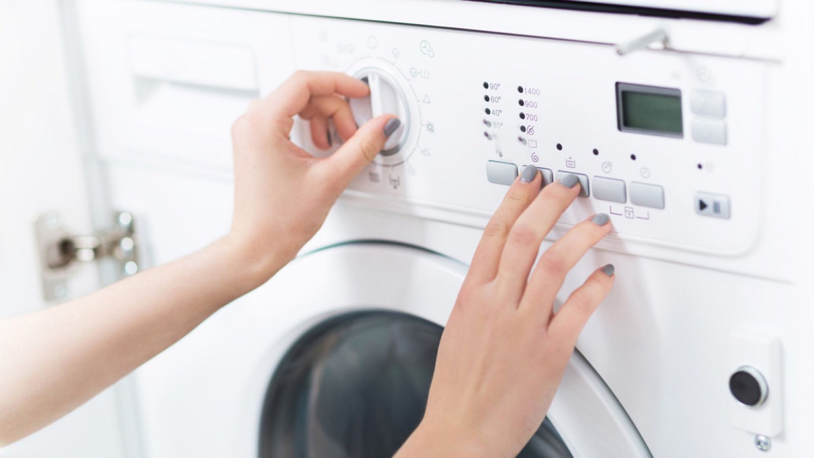 Una mujer programa una lavadora