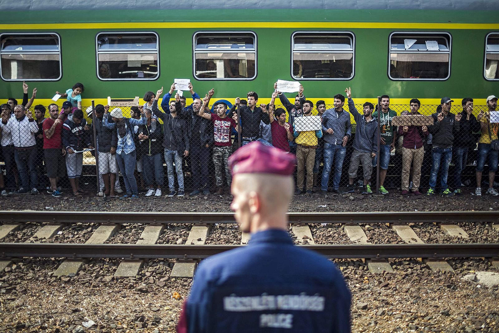 Un policía vigila mientras refugiados piden poder continuar su viaje rumbo a Europa Occidental en la estación ferroviaria de Bicske (Hungría) el pasado 4 de septiembre.
