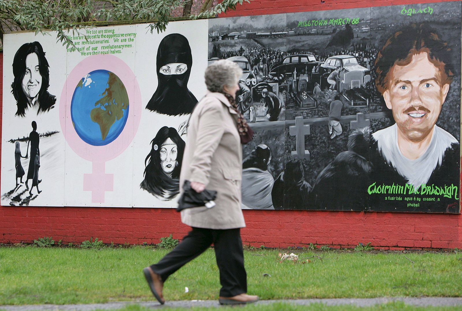 Una mujer pasa al lado de una pintura mural sobre el IRA en Belfast, Irlanda del Norte.