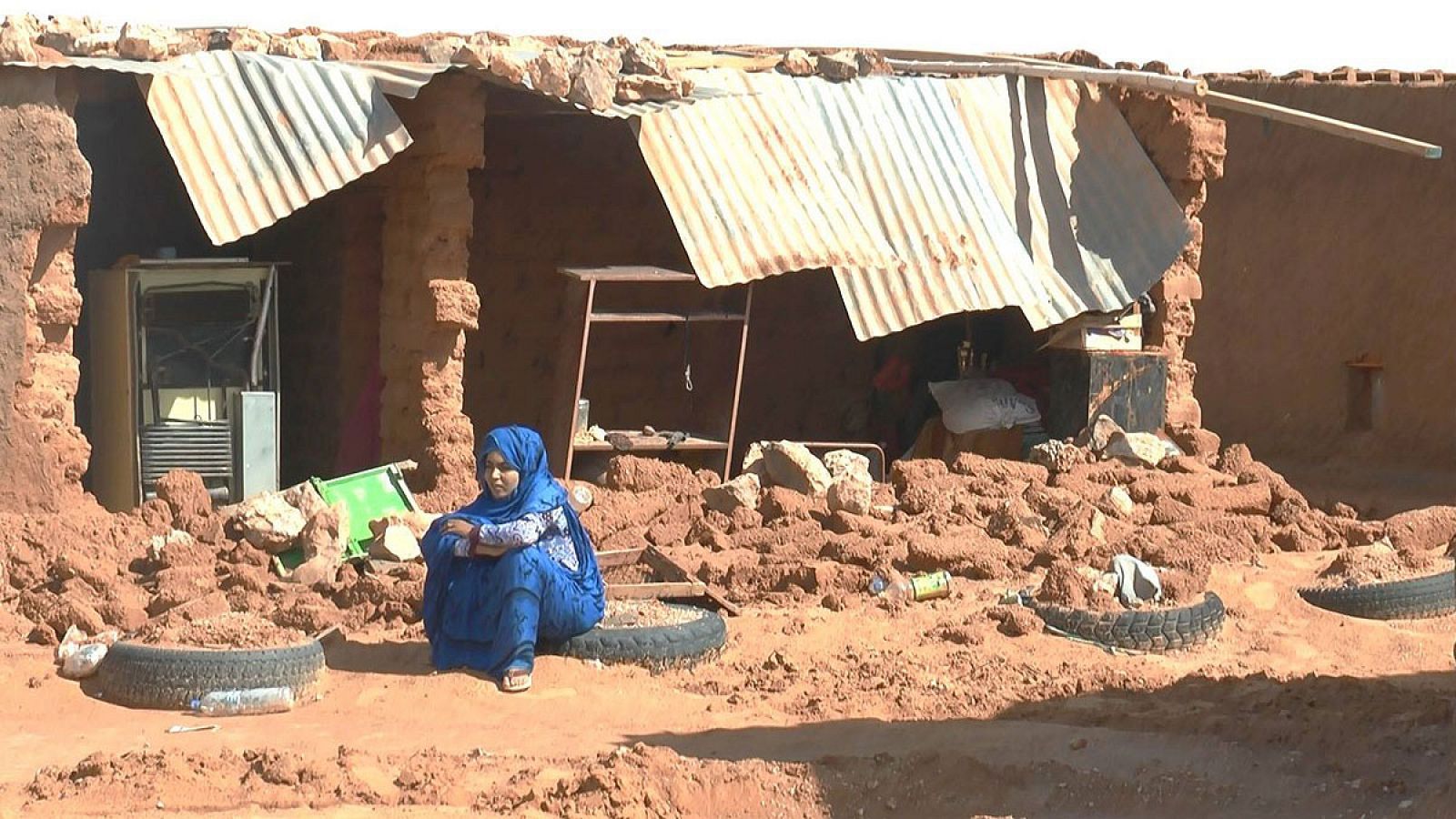 Un mujer sentada junto a los escombros provocados por las lluvias en un campo saharaui