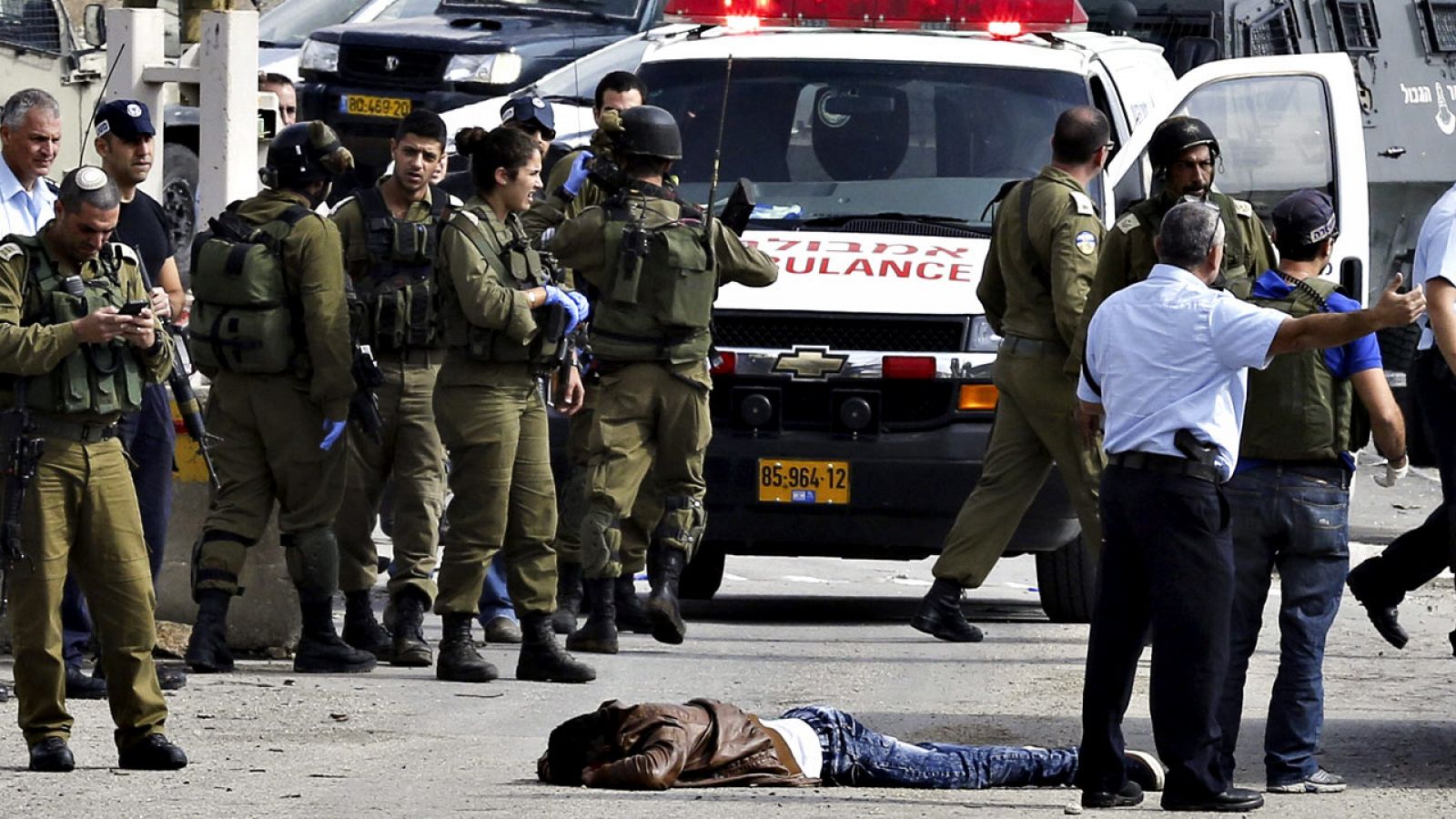 Policías y soldados israelíes inspeccionan el cuerpo sin vida del palestino de 22 años Raeed Jaradat.
