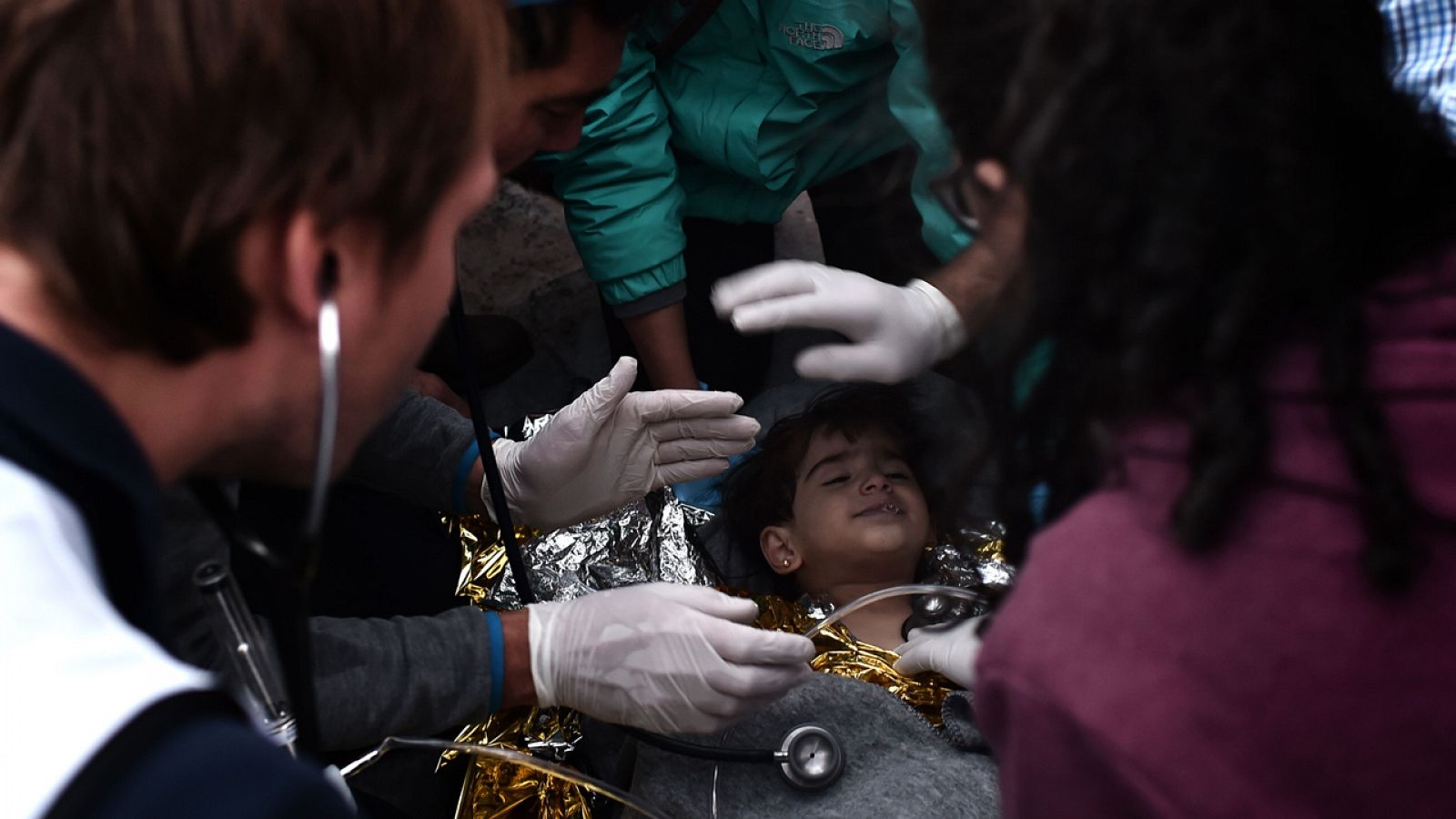 Personal sanitario atiende a un niño migrante rescatado tras un naufragio frente a la costa griega
