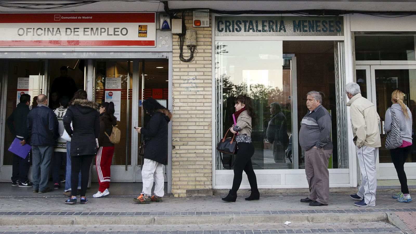 Varias personas esperan a la entrada de una oficina de empleo en Madrid