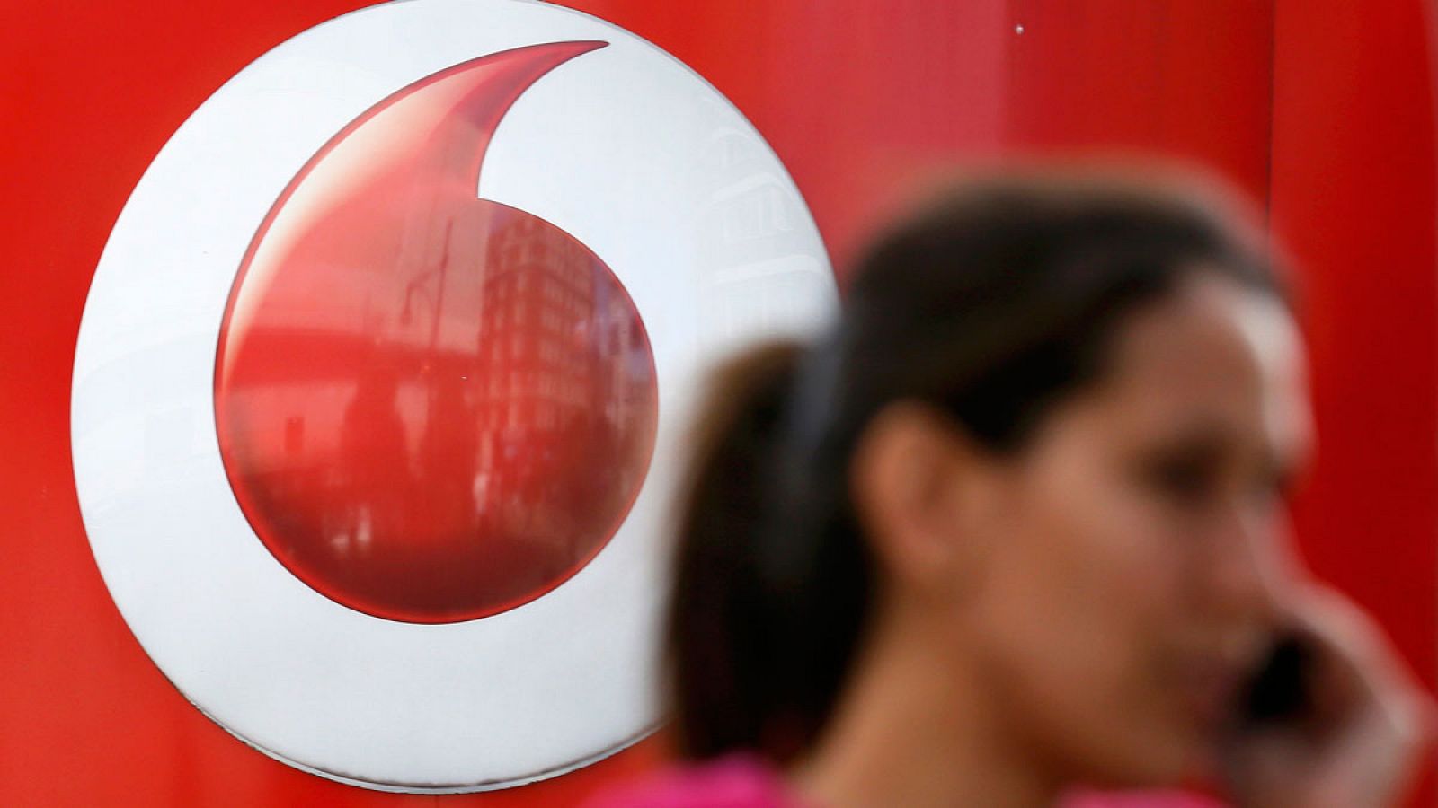 Una mujer habla por teléfono móvil en una tienda de Vodafone en el centro de Londres