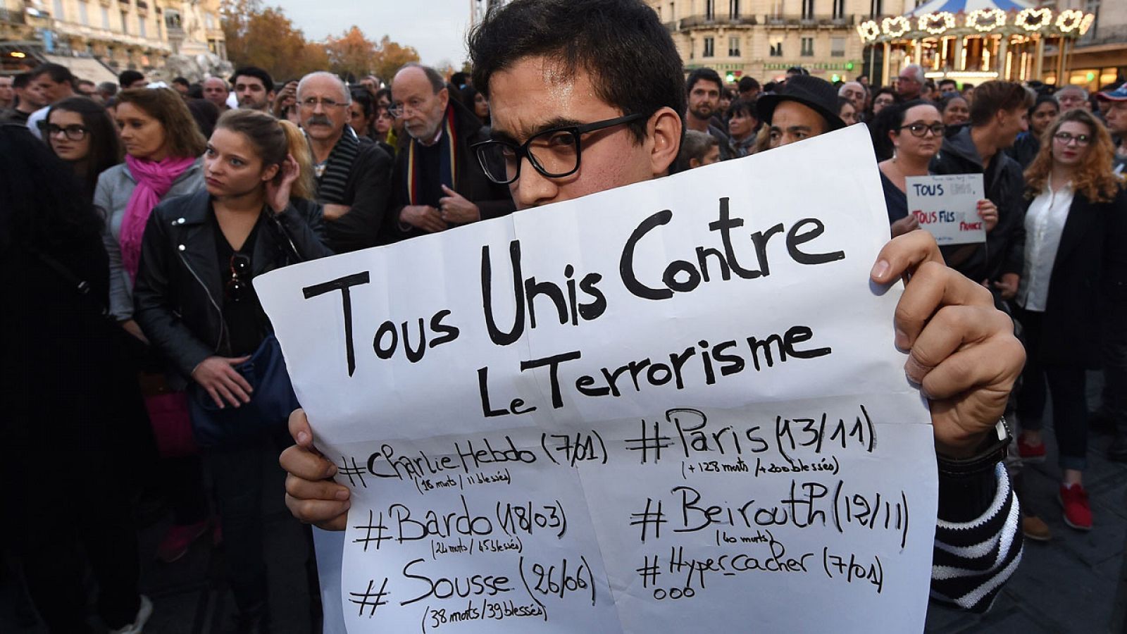 Un joven recuerda los últimos atentados yihadistas con un cartel acompañado de una multitud de franceses concentrados en Montpellier.