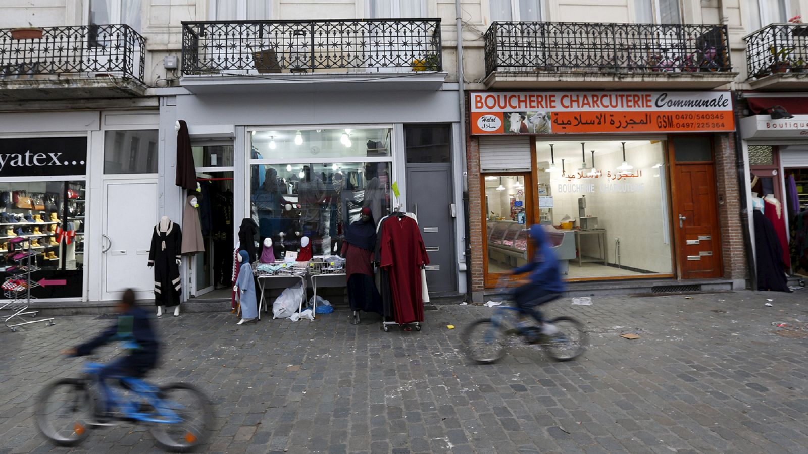 Unos jóvenes circulan en bicicleta cerca de unas tiendas en el barrio de Molenbeek, en Bruselas, Bélgica