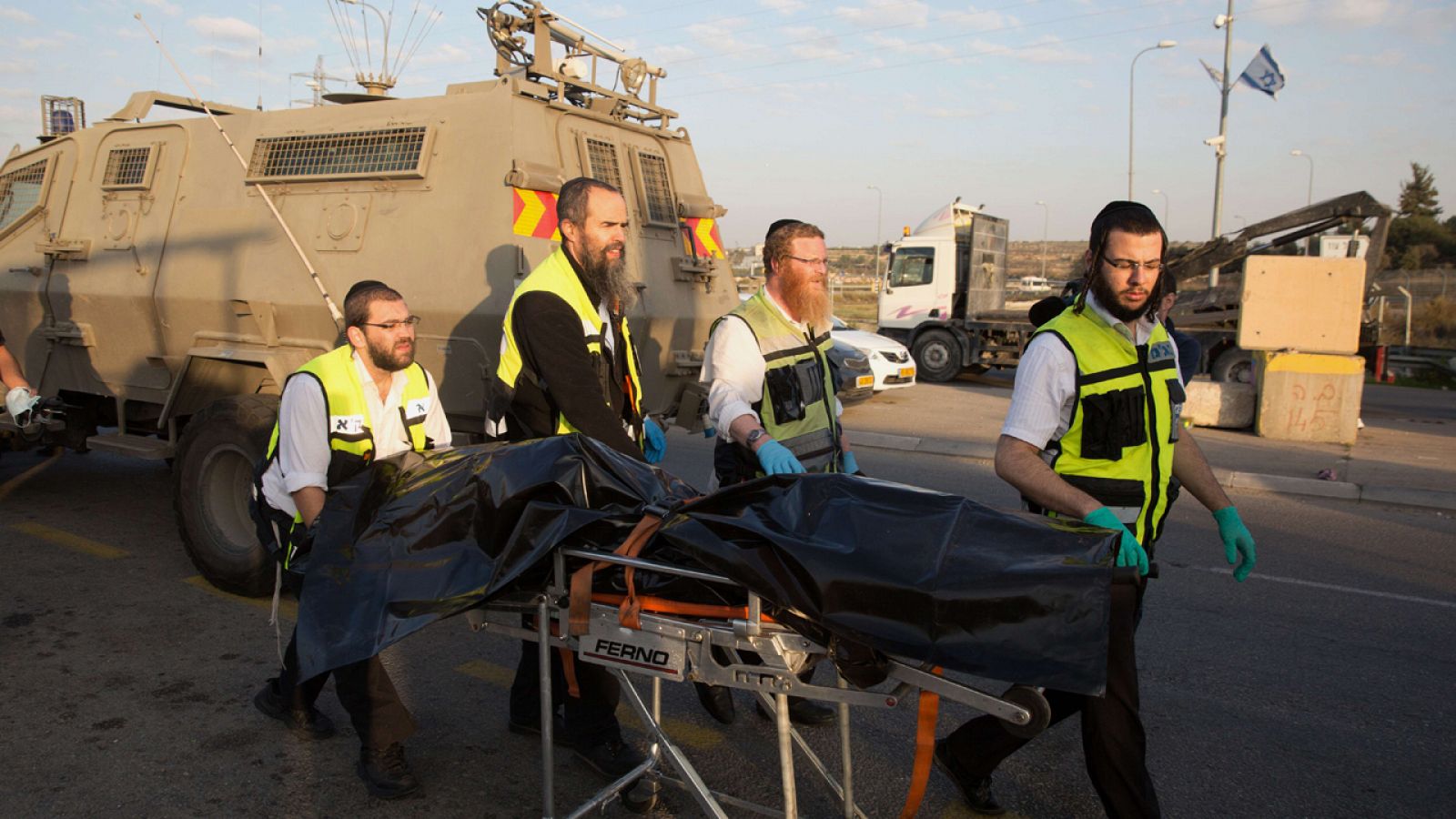 Voluntarios israelíes transportan el cuerpo de un palestino muerto tras apuñalar a una mujer israelí