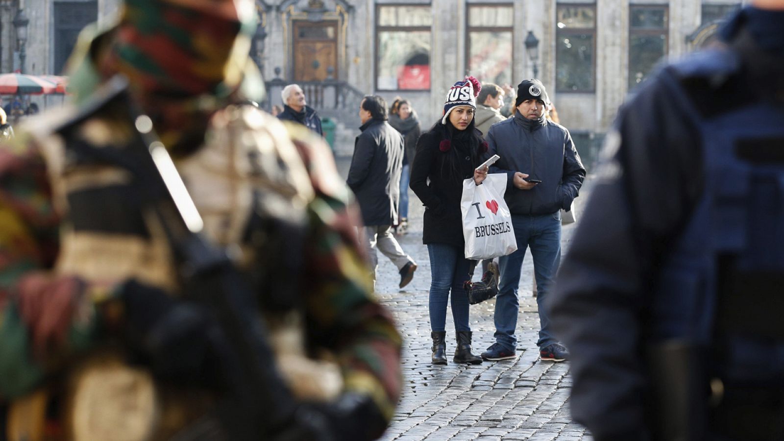 Una pareja de turistas observa a los policías y soldados desplegados en la Grand Place de Bruselas