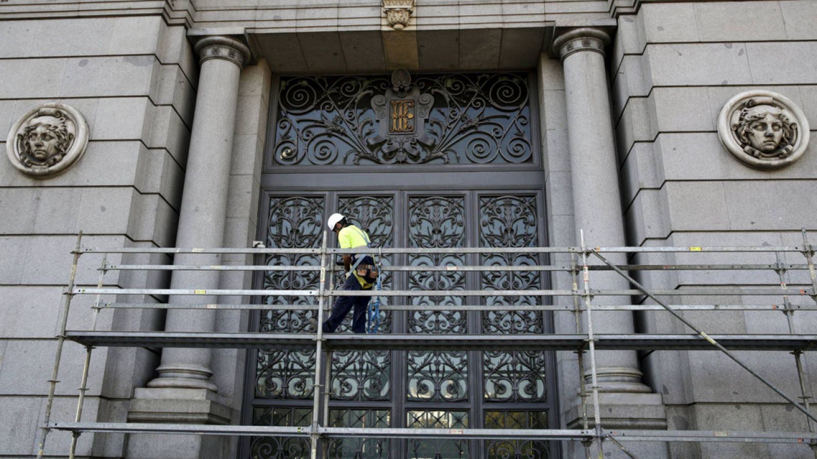 Un trabajador encima de un andamio ante la puerta del Banco de España