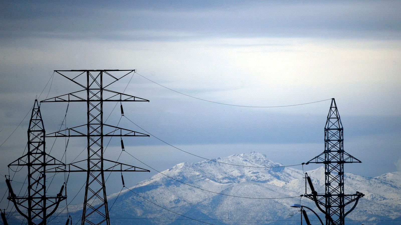 Torres de alta tensión se recortan contra las montañas nevadas que rodean la ciudad de Valencia