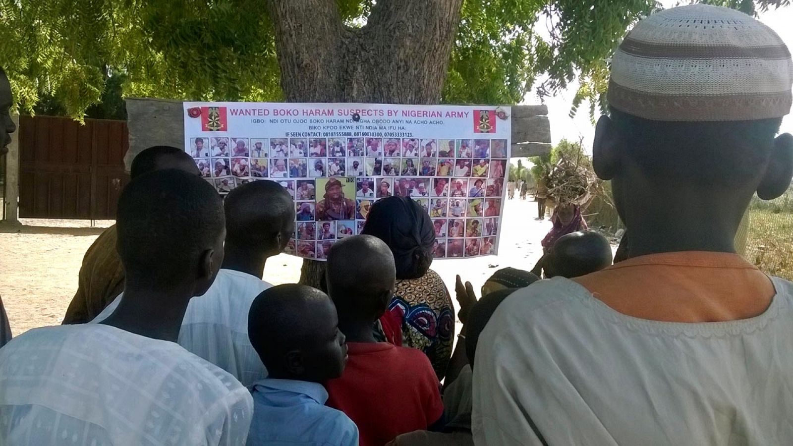Un grupo de nigerianos observa un cartel con fotos de presuntos terroristas de Boko Haram en busca y captura
